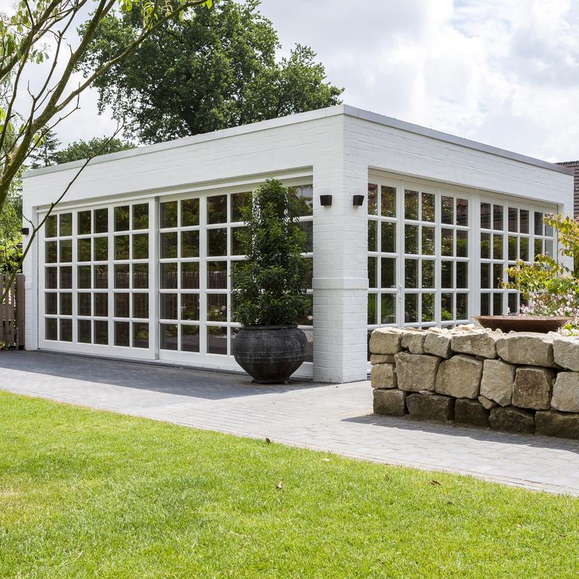 Weißer Bungalow mit Sprossenfenstern vor grüner Wiese