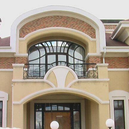 Gelbe Hausfassade mit großer Fensterfront und Rundbogen