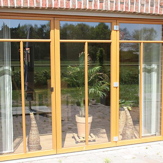 Bodentiefe Fenster mit Holzrahmen als Terassenzugang in Ziegelwand