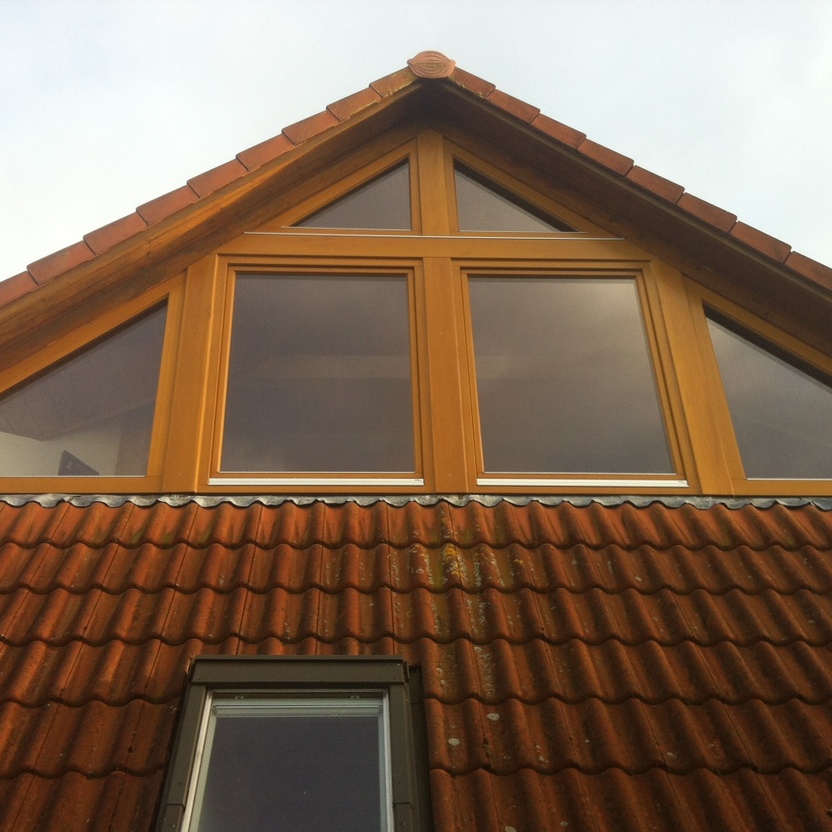 Spitzdach mit großer Fensterfront über Dachziegeln