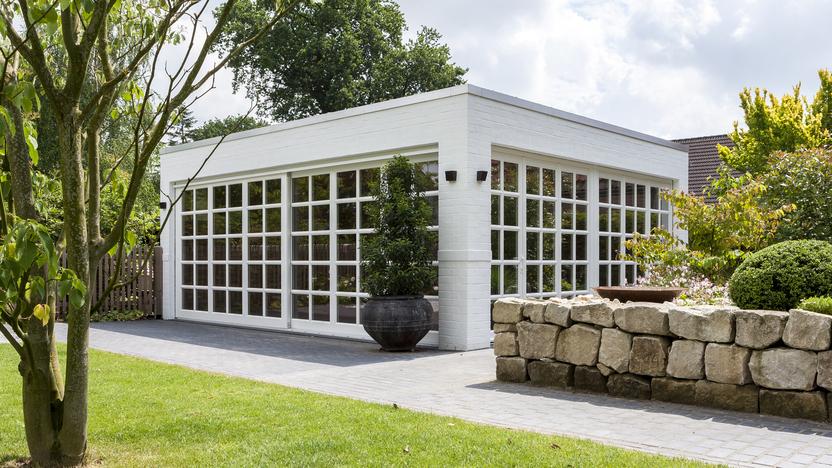 Weißer Bungalow mit Sprossenfenstern vor grüner Wiese