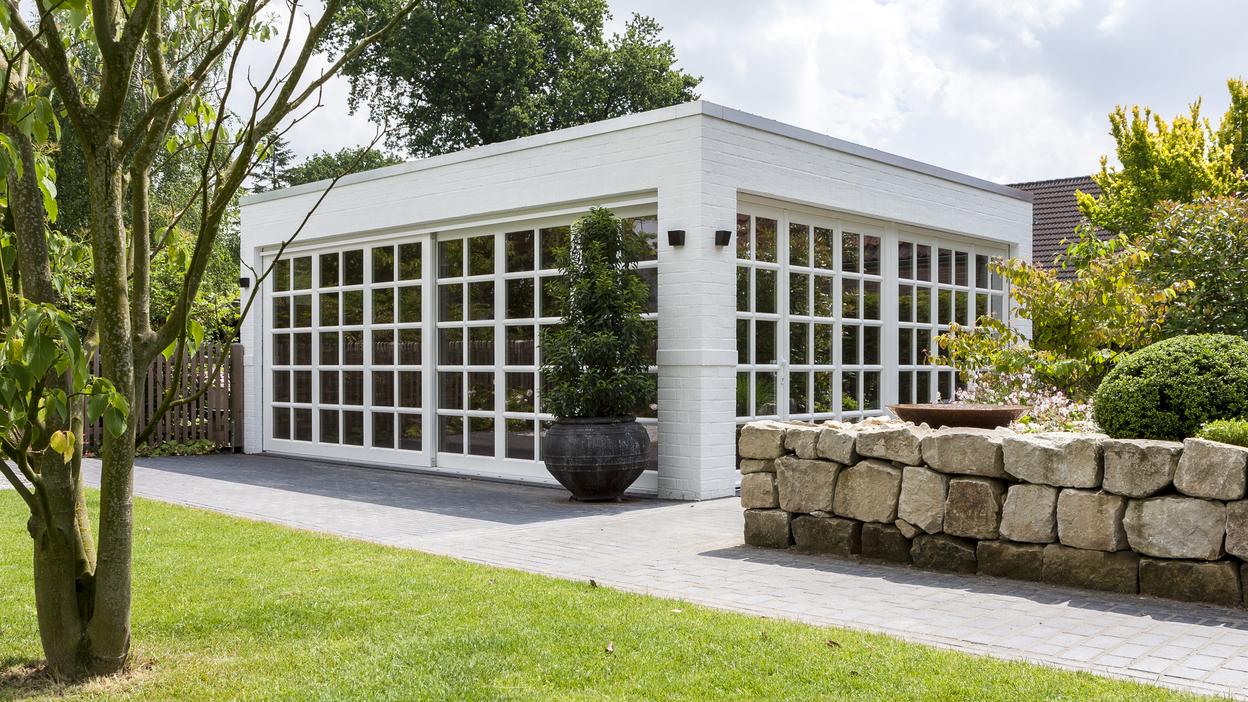 Weißer Bungalow mit Sprossenfenstern vor grüner Wiese