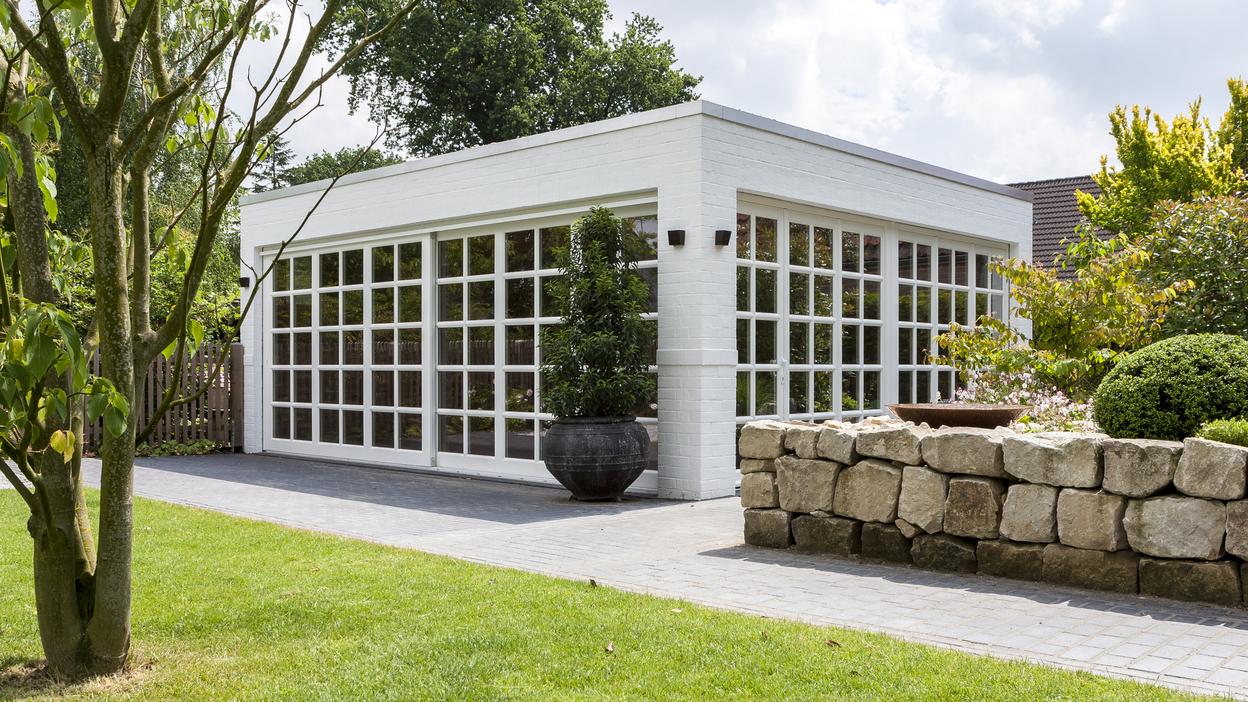 Weißer Bungalow mit Sprossenfenstern vor grüner Wiese