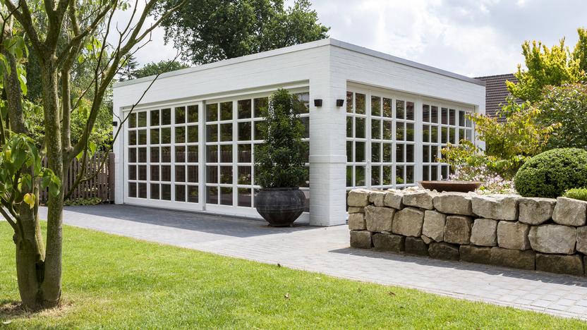 Bungalow mit Sprossenfenstern Weißer Bungalow mit Sprossenfenstern vor grüner Wiese