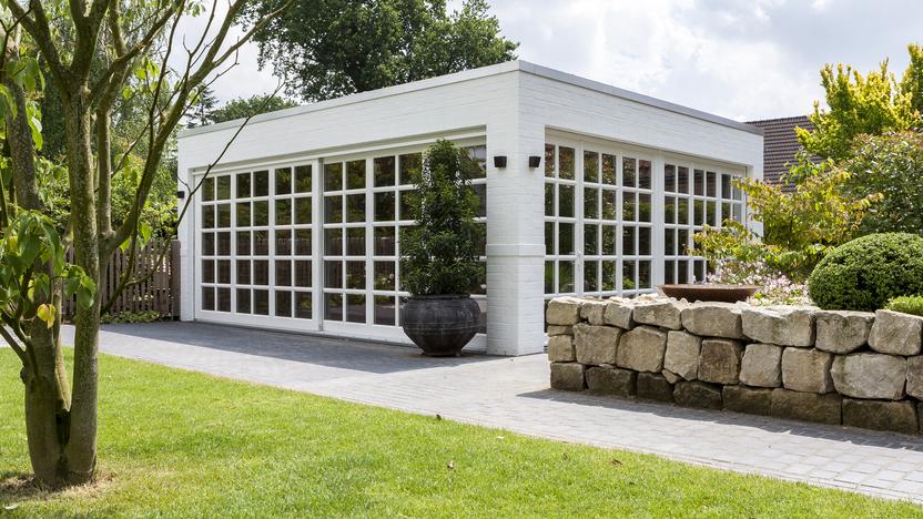 Weißer Bungalow mit Sprossenfenstern vor grüner Wiese
