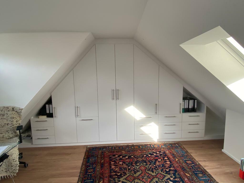 Einbauschrank aus weißem Holz unter Dachschräge