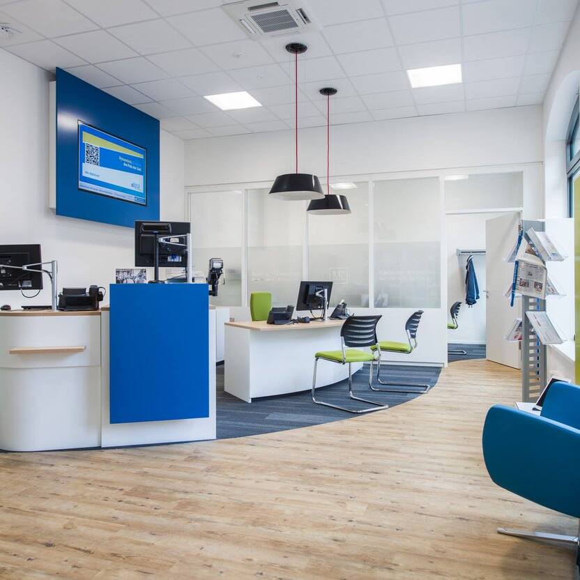 Blauer Sessel auf Holzboden vor Empfangstresen in einer Praxis