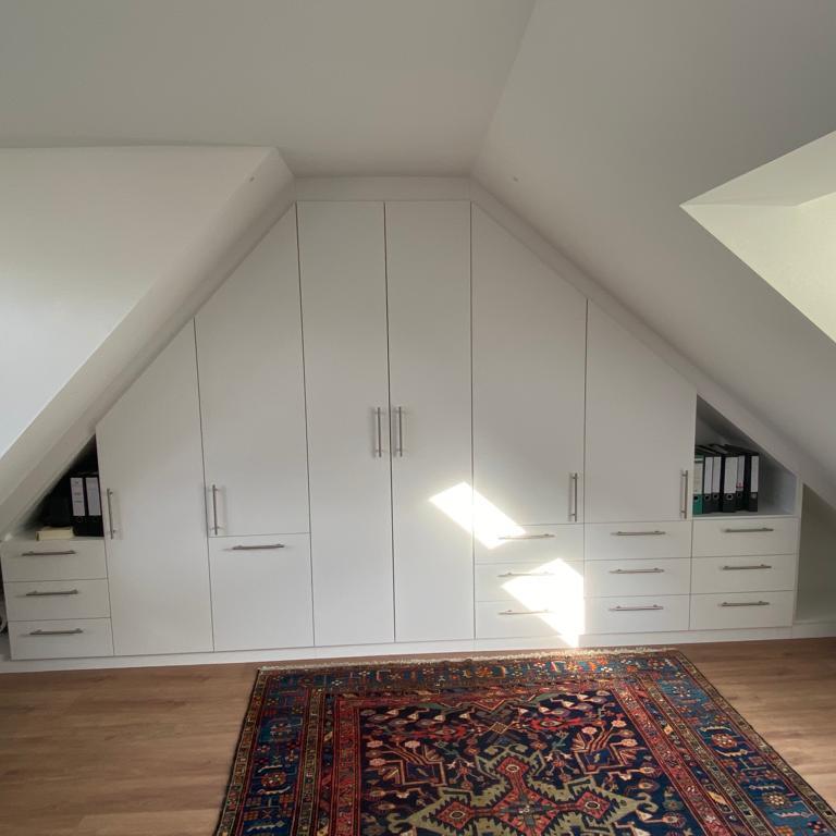Einbauschrank aus weißem Holz unter Dachschräge