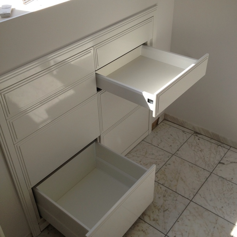 Moderner weißer Schrank mit zwei offenen Schubladen und Marmorboden in einem hochwertigen Innenausbau.