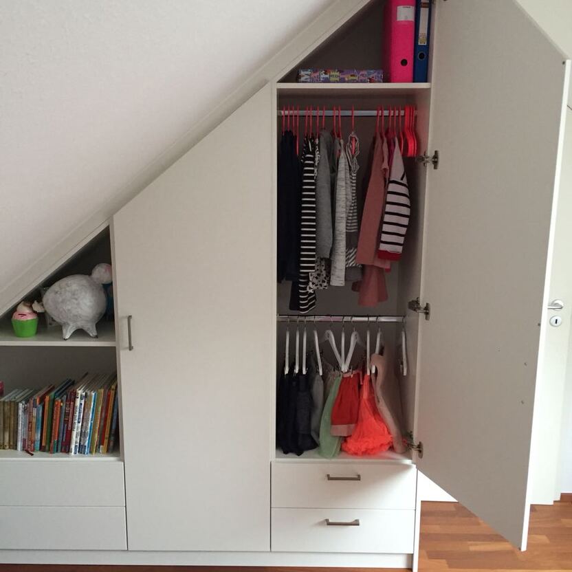 Weißer Dachschrägenschrank mit offener Tür und Blick auf Anziehsachen