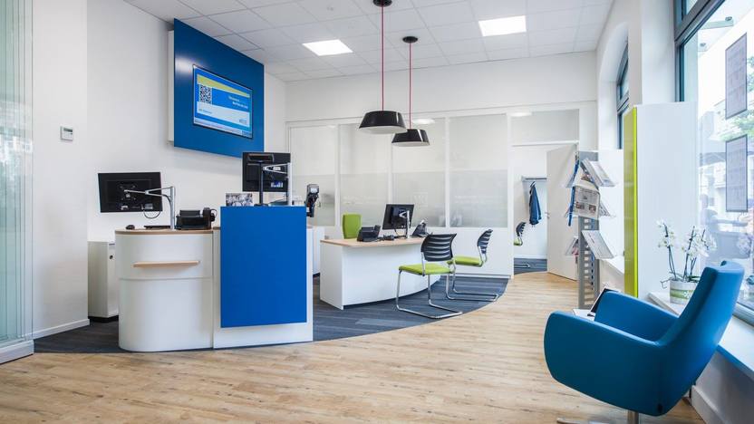 Blauer Sessel auf Holzboden vor Empfangstresen in einer Praxis