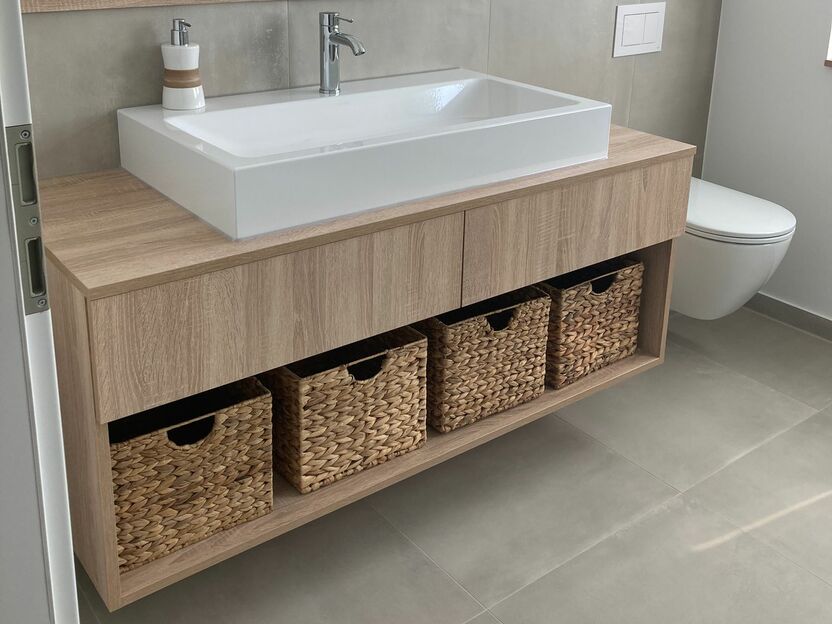 Waschbeckenunterschrank aus Holz mit vier Körben unter weißem Waschbecken