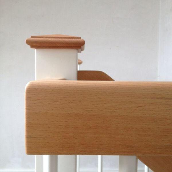 Nahaufnahme eines Treppengeländers mit hellen Buchenholz-Handläufen und weißen Pfosten in einem modernen Innenraum.