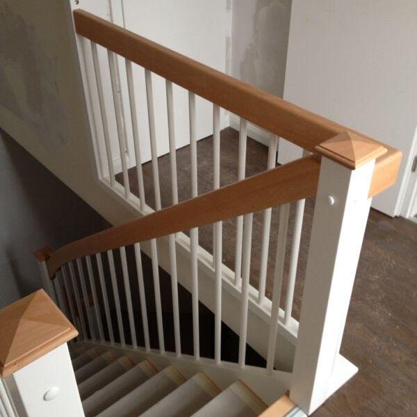 Gerade Innentreppe mit weißen Geländerstäben und hellen Buchenholz-Handläufen in einem Wohnhaus.