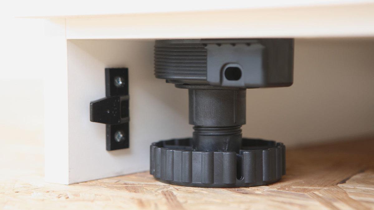 Detailaufnahme eines verstellbaren Sockels Detailaufnahme eines verstellbaren schwarzen Bodensockels mit Schraubmechanismus