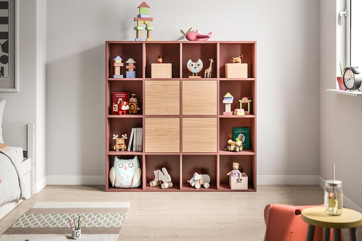 Farbenfroher, maßgefertigter Spielzeugschrank im Kinderzimmer. Ein Schrank nach Maß in Terrakottafarbe mit offenen und geschlossenen Fächern, befüllt mit Spielzeug und Büchern, bietet spielerische Ordnung im Kinderzimmer.